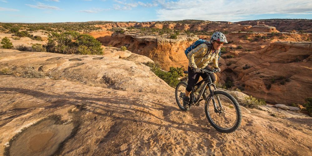 A man is riding a mountain bike on a dirt trail in the desert.