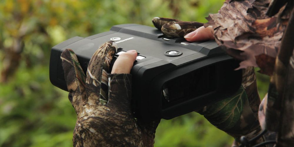 A person wearing gloves is holding a camera in their hands.