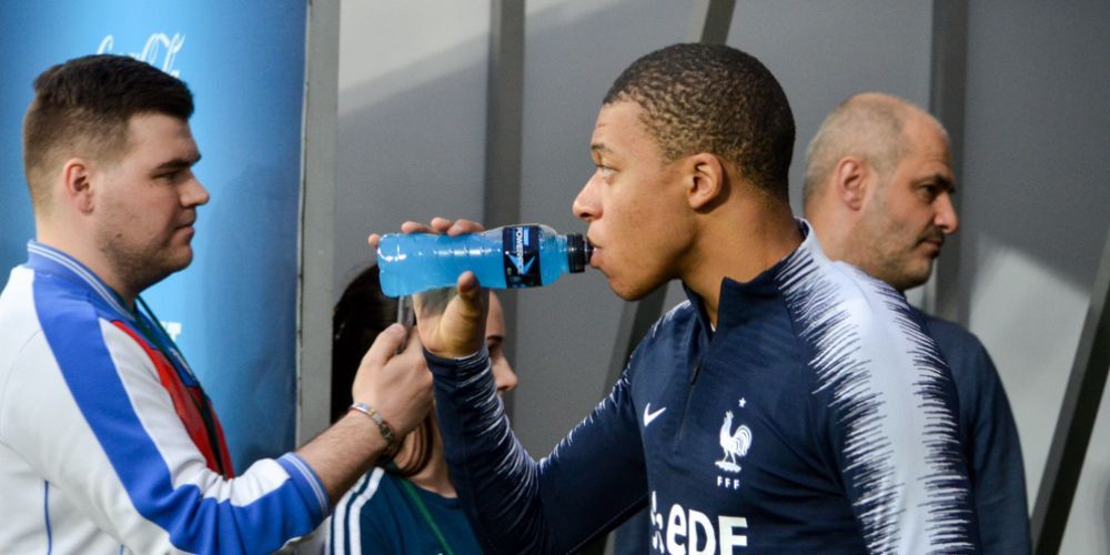 A man is giving a bottle of water to a soccer player.