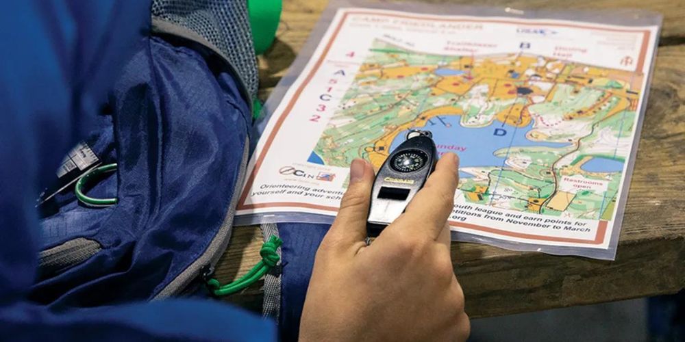 A person is holding a compass in front of a map.