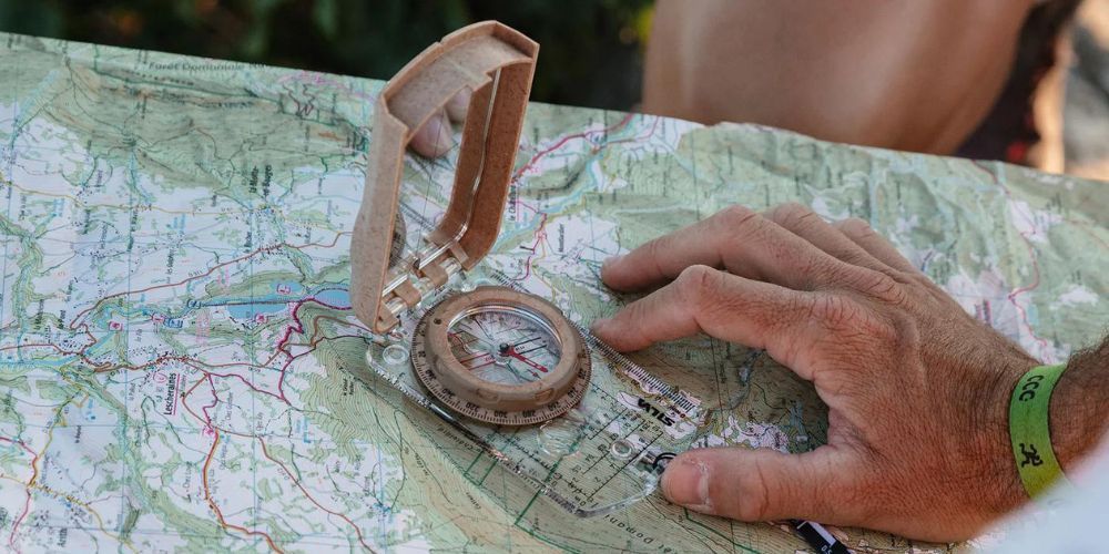 A person is holding a compass over a map.