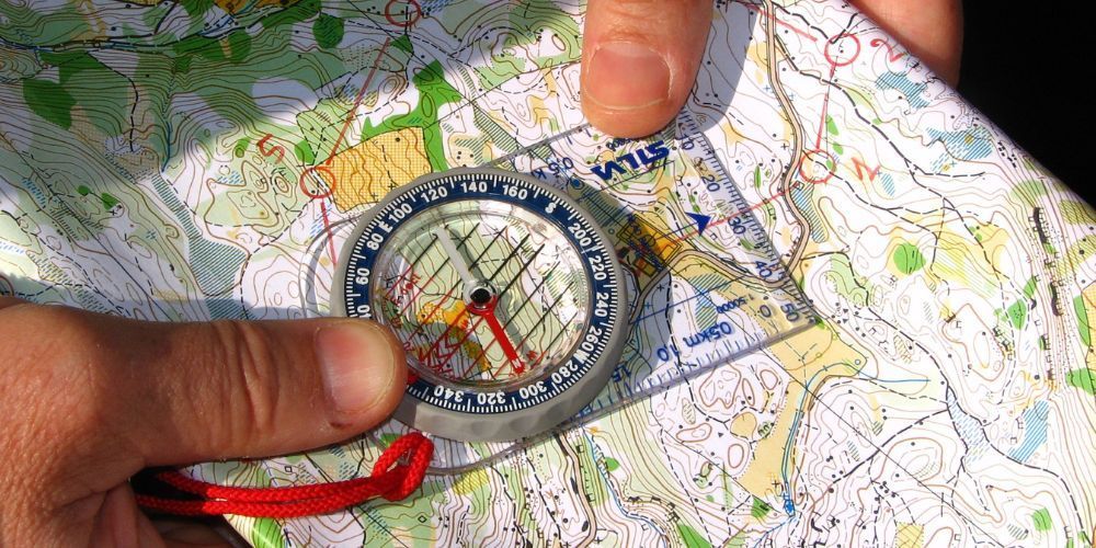 A person is holding a compass over a map.