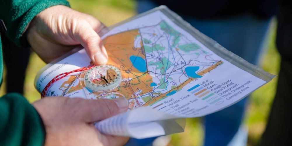 A person is holding a map and compass in their hands.