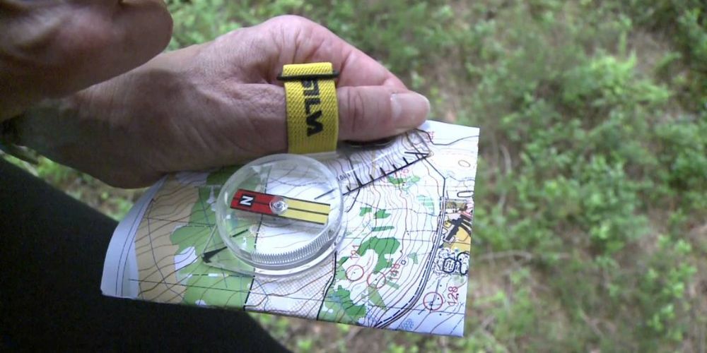 A person is holding a compass and a map in their hand.