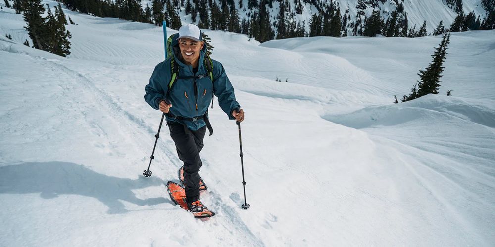 A man is walking through the snow on snowshoes.