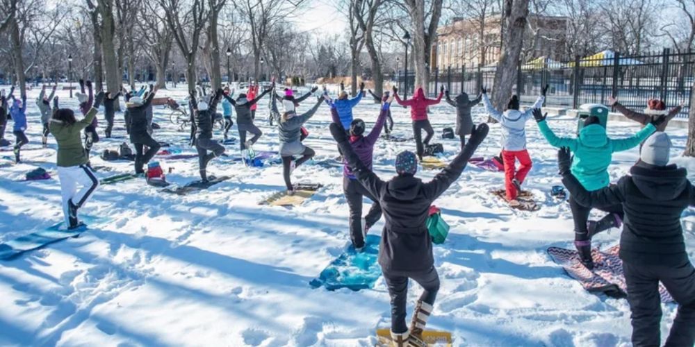 A group of people are doing yoga in the snow.