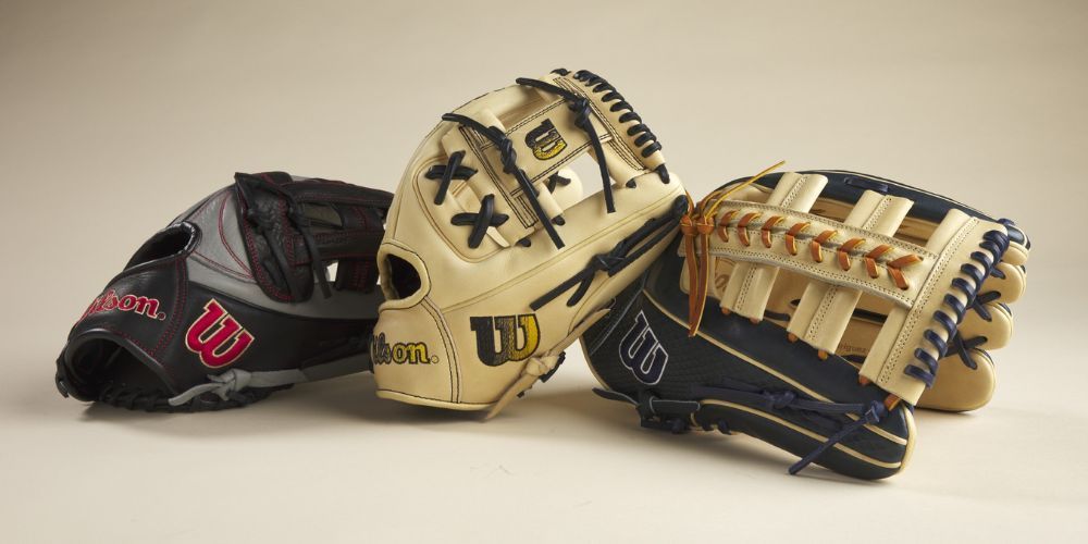 Three wilson baseball gloves are stacked on top of each other on a white surface.