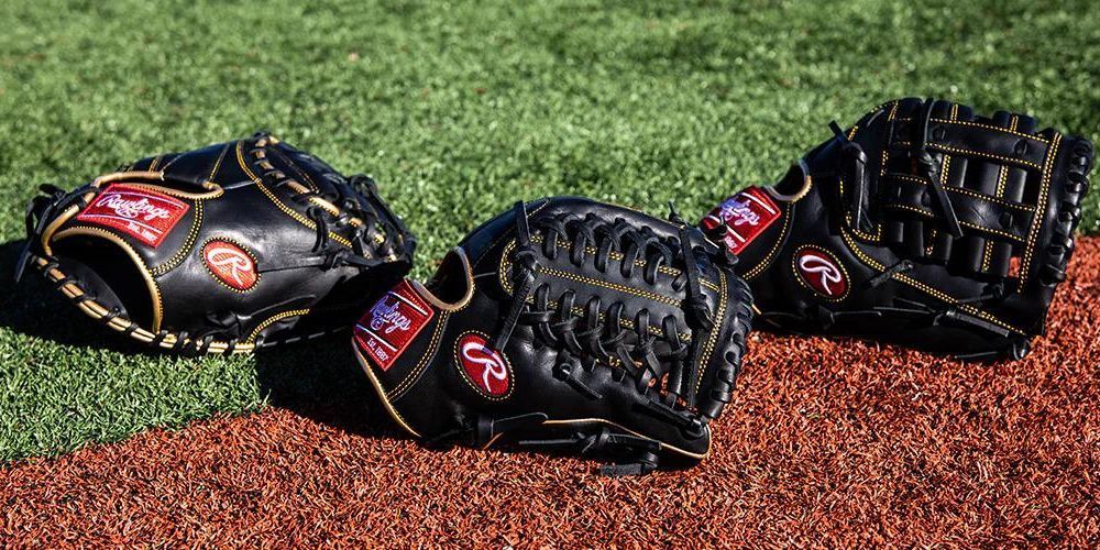 Three baseball gloves are sitting on a baseball field.