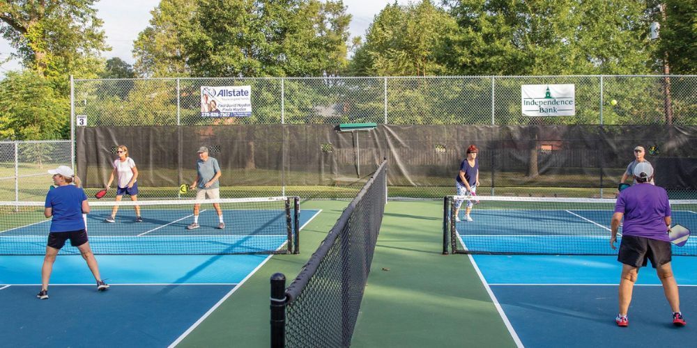 A group of people are playing pickleball on a pickleball court.