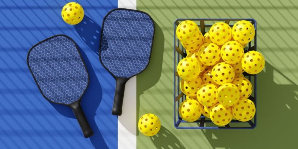 Two paddle rackets and a basket of yellow balls on a tennis court.