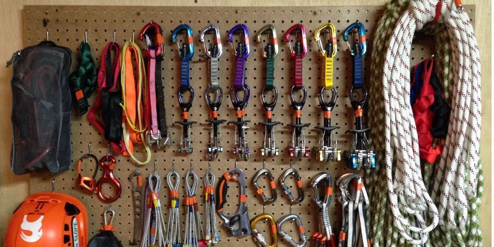 A bunch of climbing gear is hanging on a peg board.