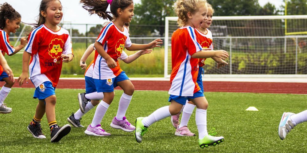 A group of young girls are running on a soccer field.