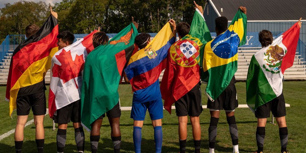 A group of soccer players are standing on a field holding up their flags.