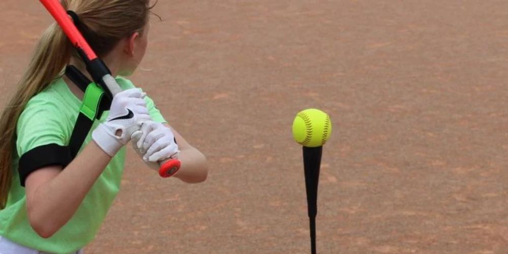 girl hitting softball off a tee