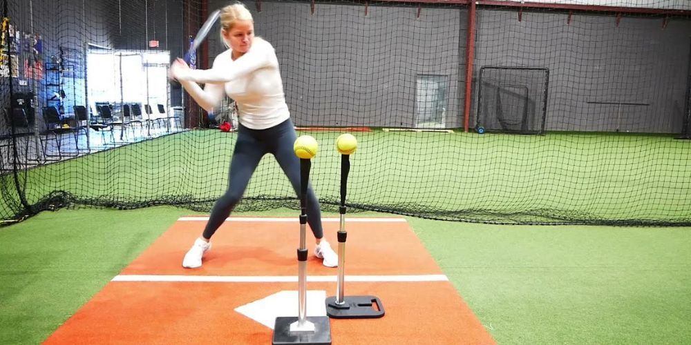 A woman is swinging a bat on a baseball field.