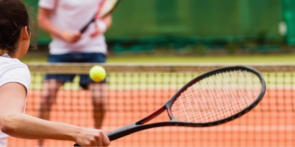 A woman is hitting a tennis ball with a racket on a tennis court.