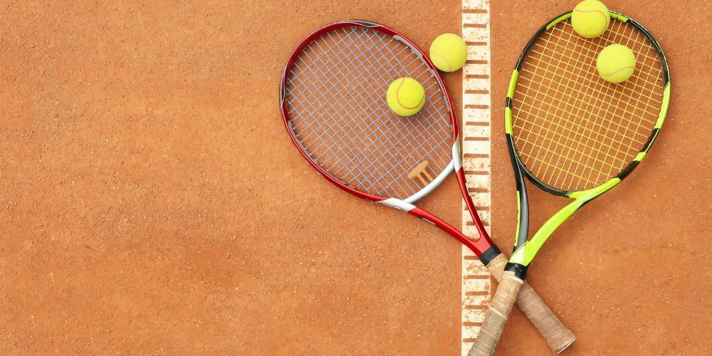 Two tennis rackets and three tennis balls on a tennis court.