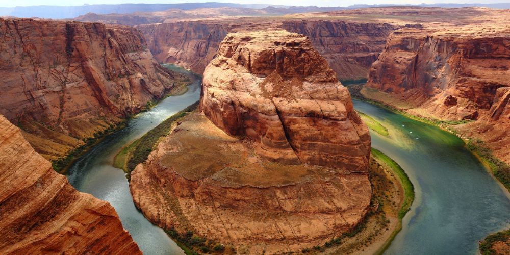 A river flowing through a canyon with a large rock in the middle.