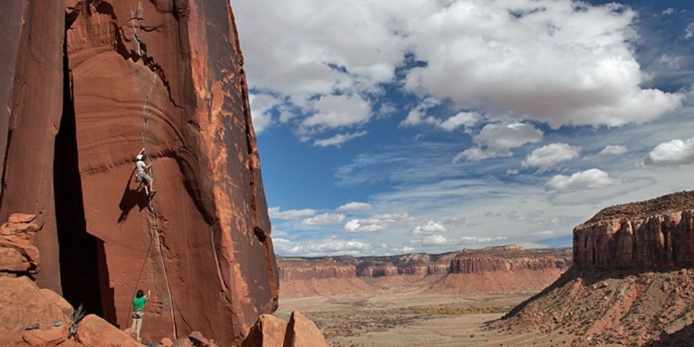 A person is climbing a rock wall in the desert.