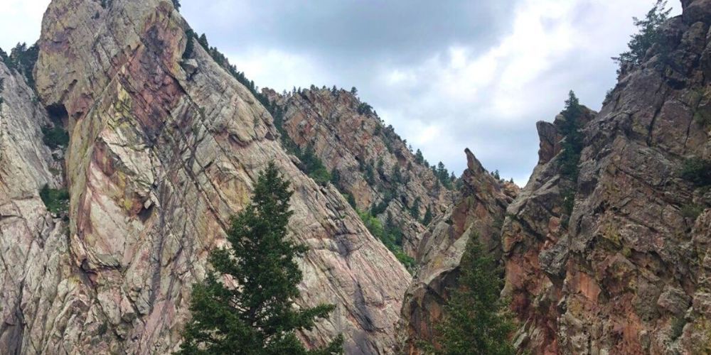 A mountain covered in rocks and trees with a cloudy sky in the background.