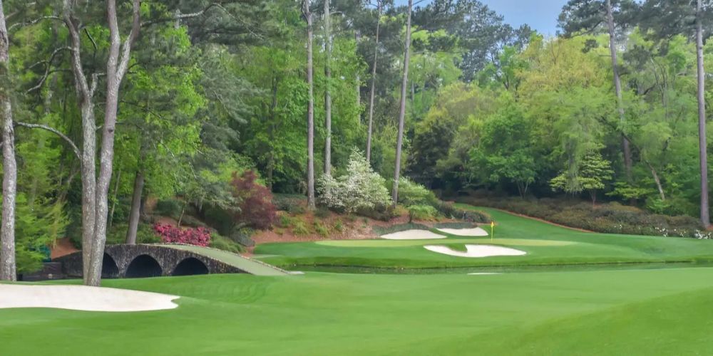 A golf course with trees and a bridge in the background.