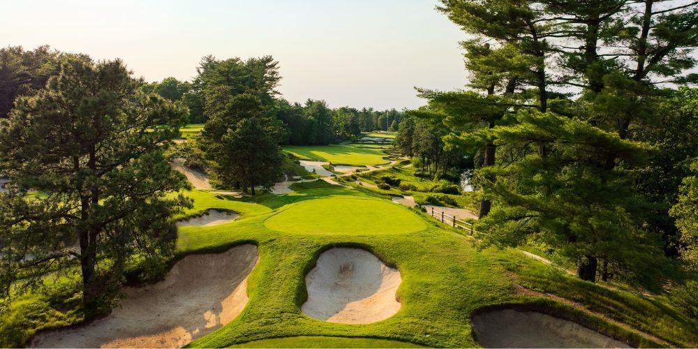 An aerial view of a golf course surrounded by trees and sand bunkers.