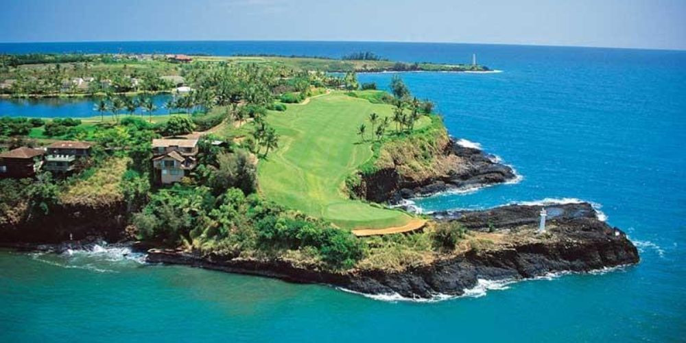 An aerial view of a golf course on a small island in the middle of the ocean.