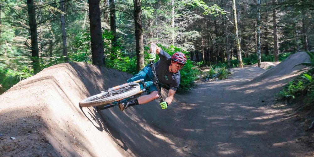 A man is doing a trick on a mountain bike in the woods.