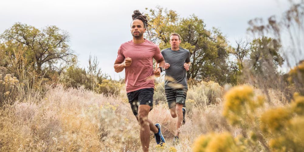 Two men are running on a trail in a field.