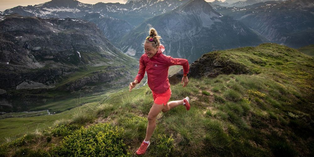 A woman is running on top of a mountain.