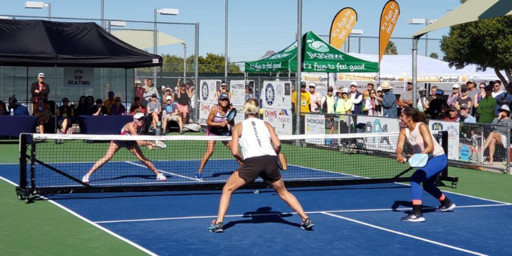 Two women are playing a game of pickleball on a court