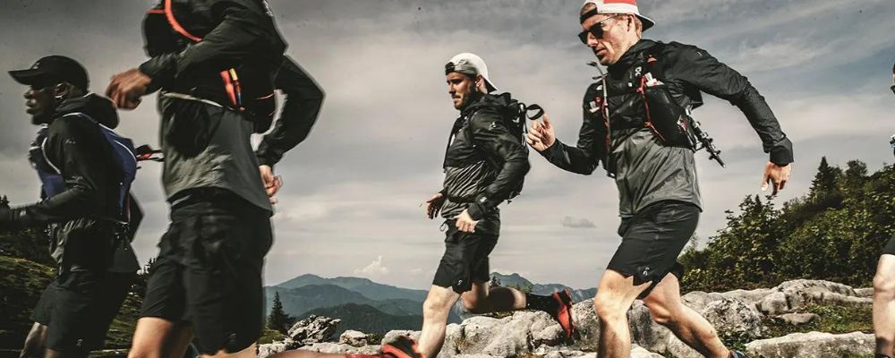 four men running on a mountain trail