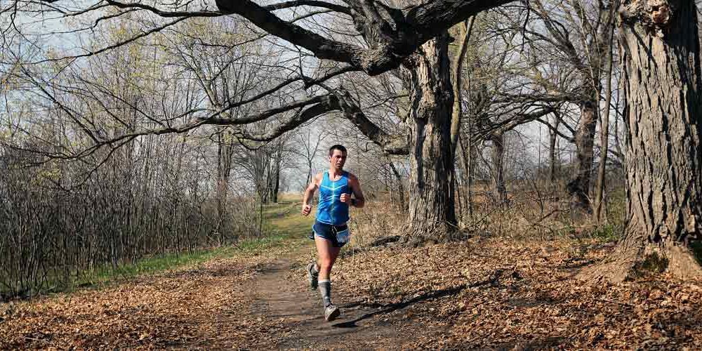 a man running on a trail in the woods
