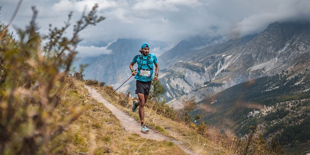 A man is running on a trail in the mountains.