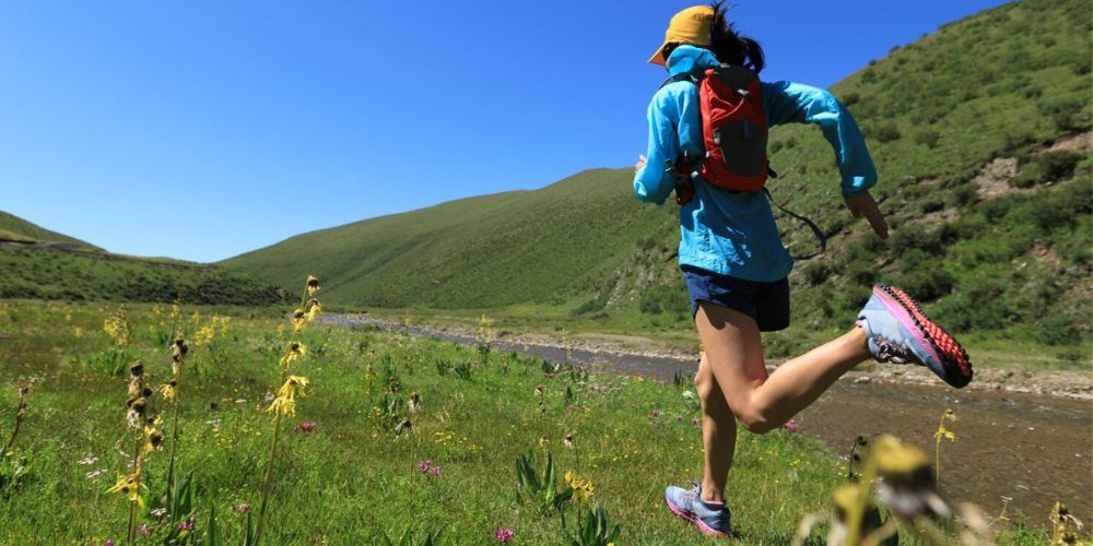 woman running on a trail wearing a trail running hat