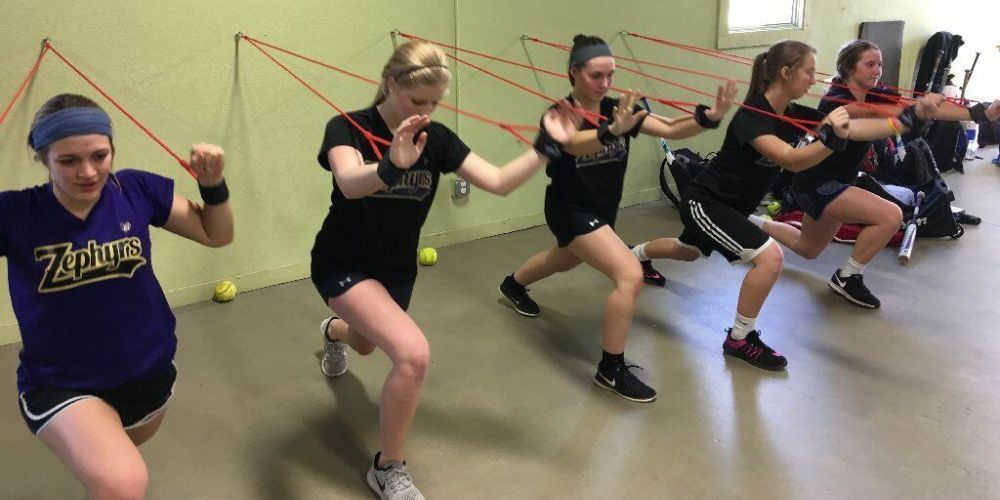 A group of young women are doing stretching exercises in a gym.