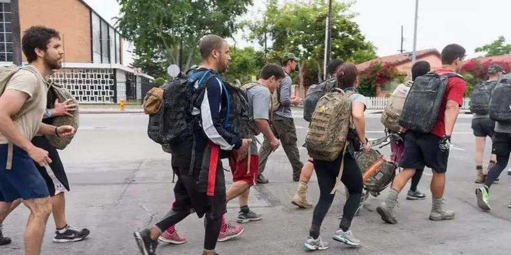 A group of people with backpacks are walking down a street.