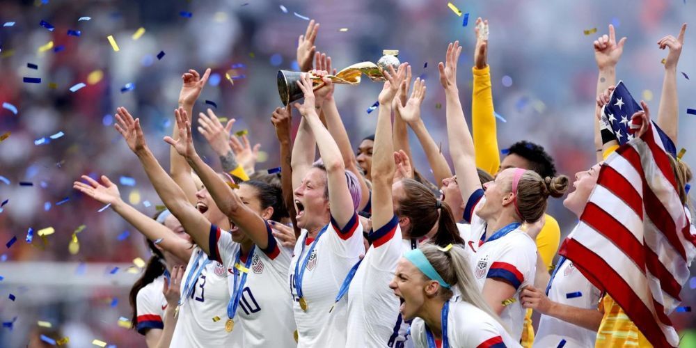 A group of soccer players are holding a trophy in the air.