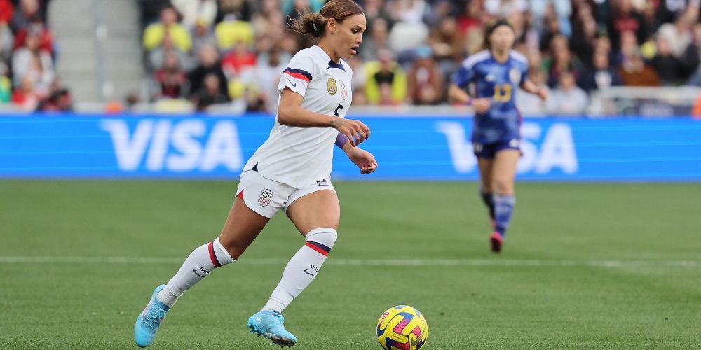 A woman is kicking a soccer ball on a field.