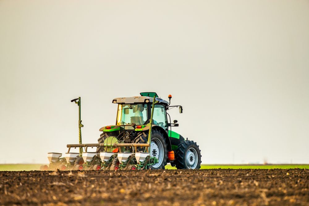 Green Tractor Plowing a Field — Paul’s Tyres & Farm Maintenance in Dubbo, NSW