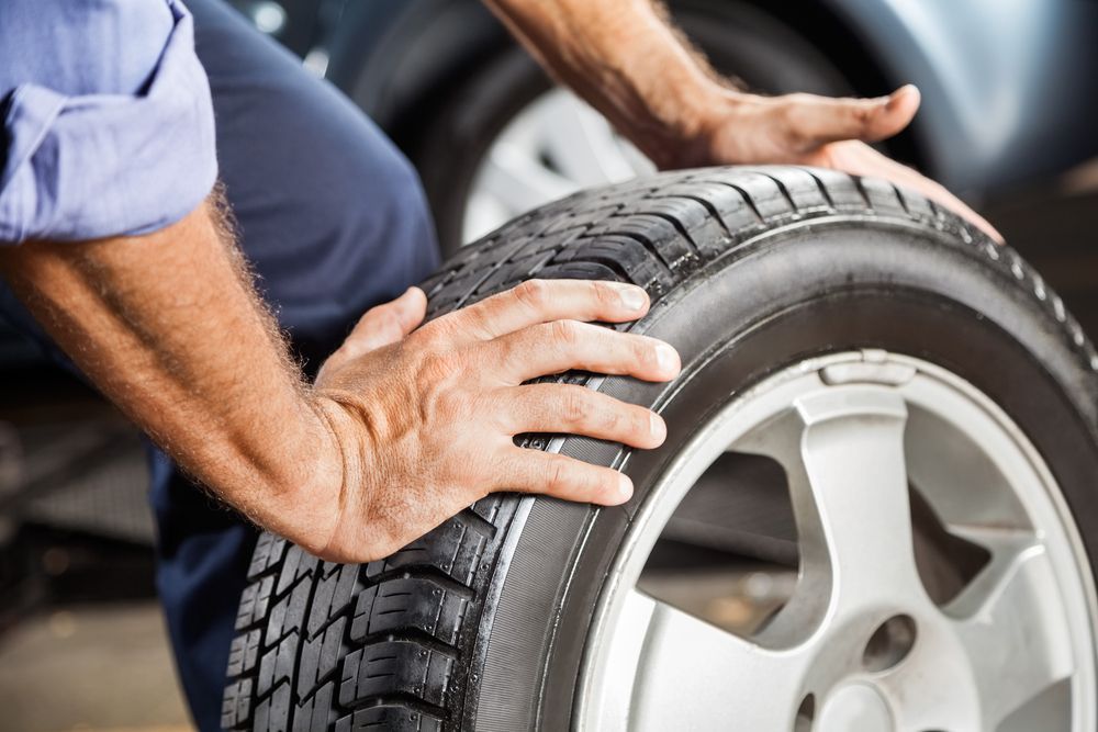 Person Changing a Car Tire, Hands on the Wheel — Paul’s Tyres & Farm Maintenance in Parkes, NSW