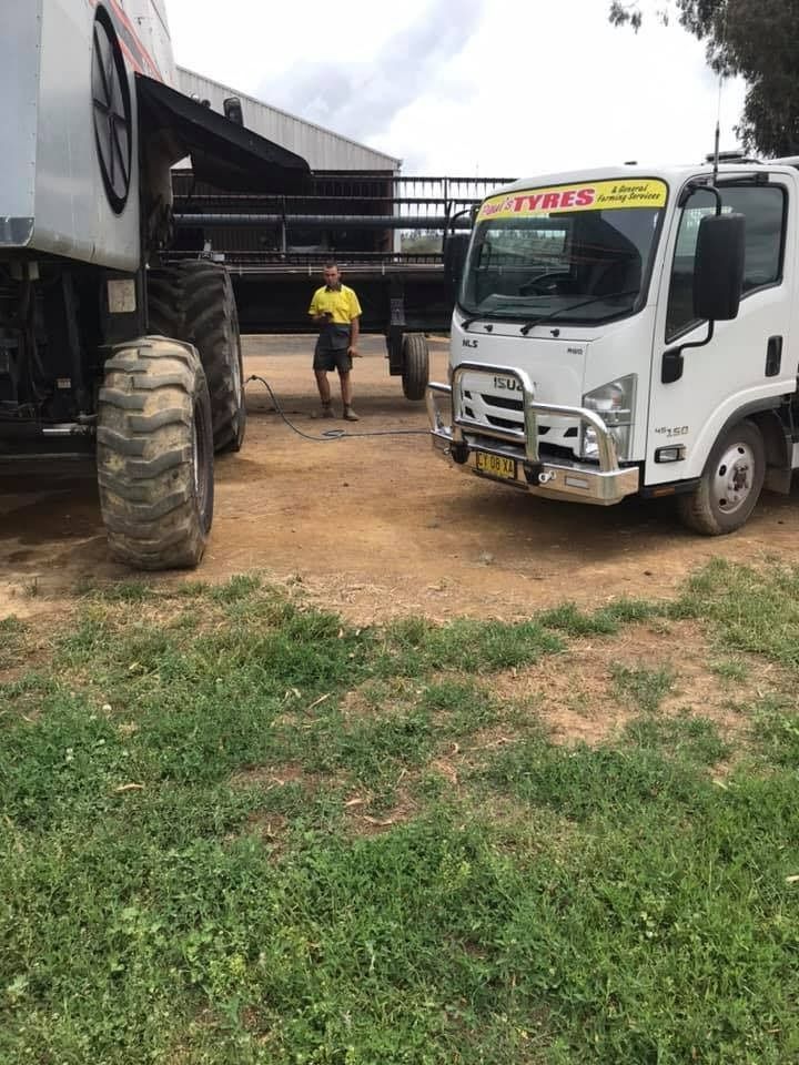 Man Standing Between a White Truck — Paul’s Tyres & Farm Maintenance in Apsley, NSW