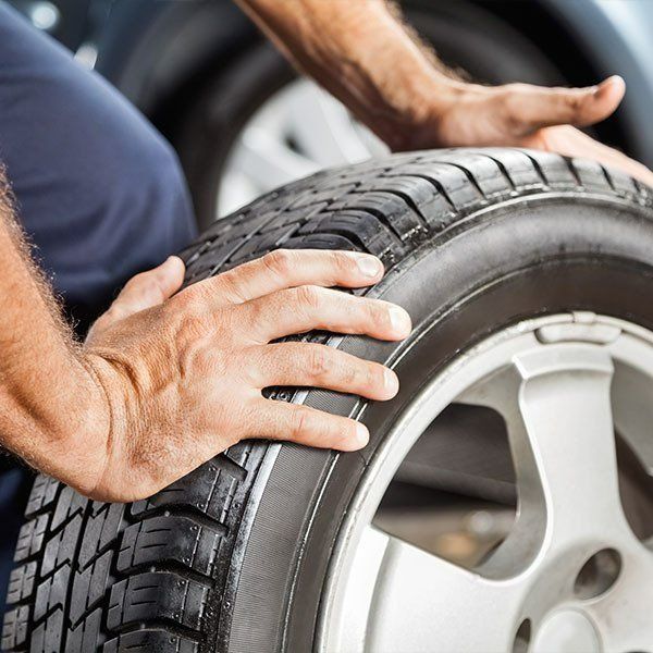 Hands Gripping a Car Tire — Paul’s Tyres & Farm Maintenance in Wellington, NSW