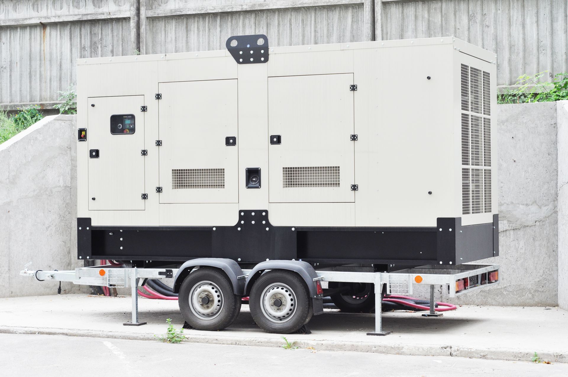 A generator is on a trailer parked on the side of the road.