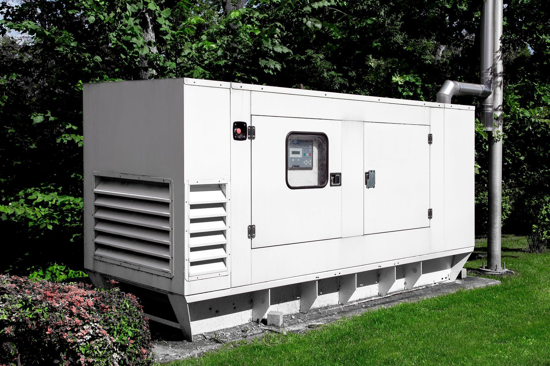 A large white generator is sitting in the middle of a lush green field.