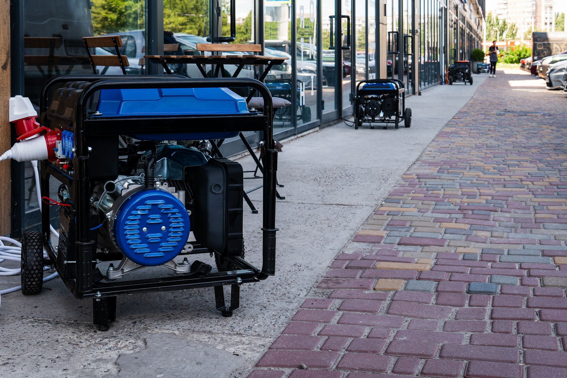 A blue generator is parked on a sidewalk next to a building.