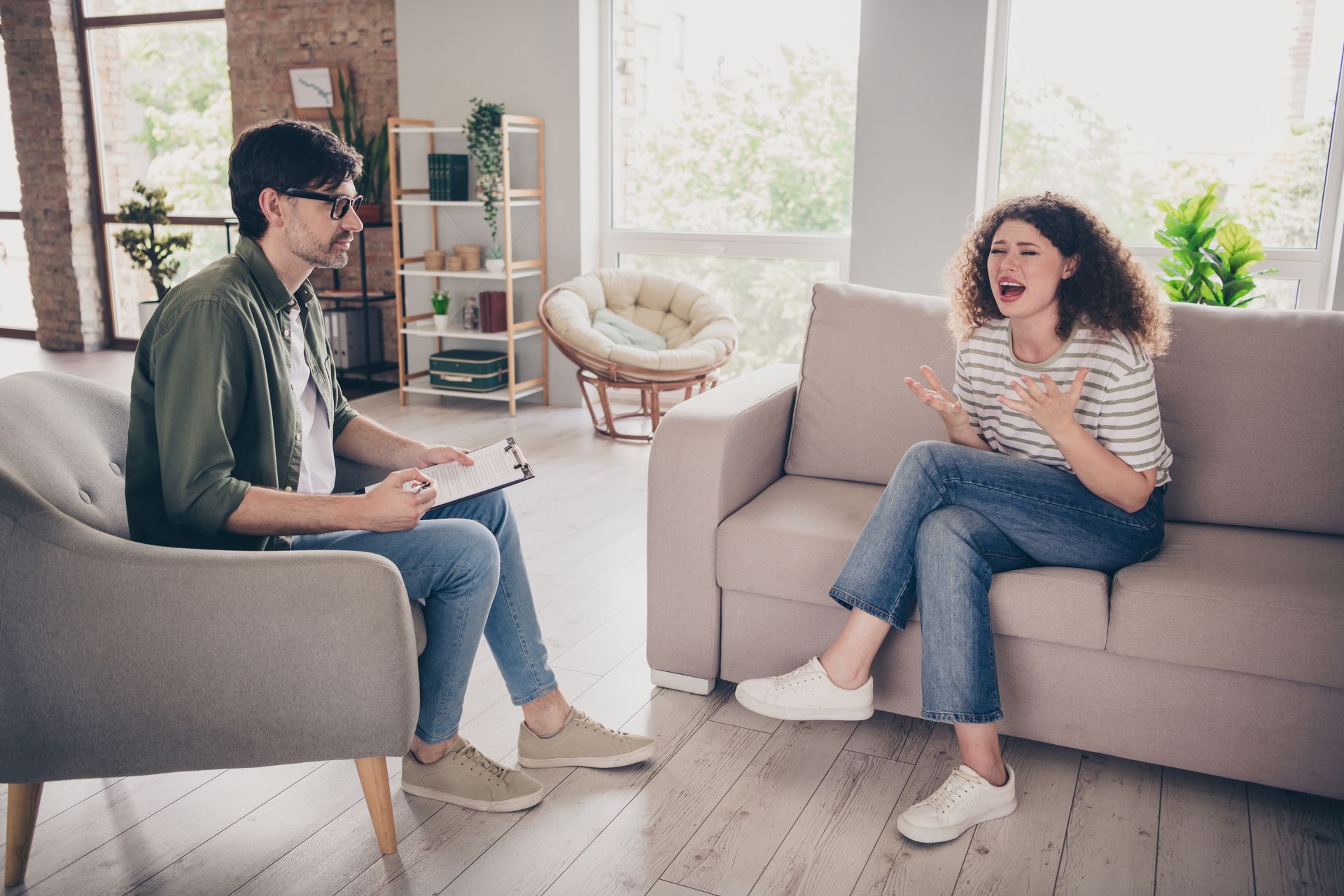 A woman is sitting on a couch talking to a man in a chair.