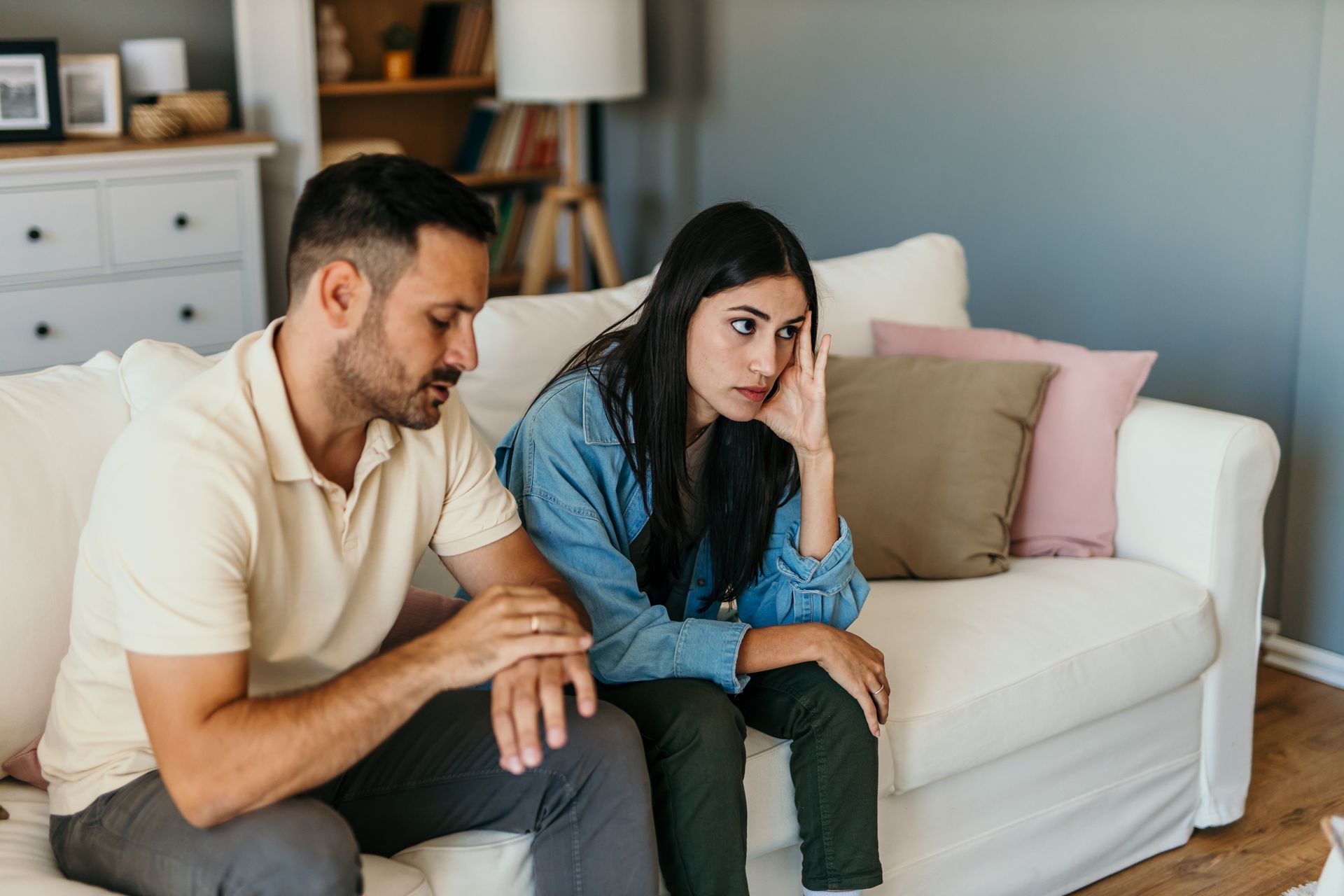 A man is comforting a woman who is sitting on a couch.