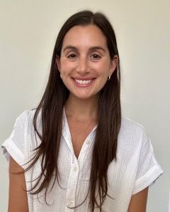 A woman with long hair is smiling for the camera while wearing a floral shirt.