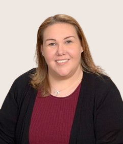 A woman wearing a black cardigan and a red shirt smiles for the camera